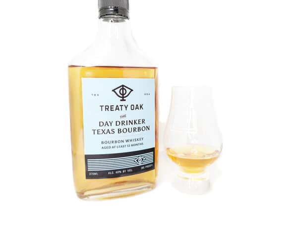 White background tasting shot with the Treaty Oak Day Drinker Bourbon bottle and a glass of whiskey next to it.