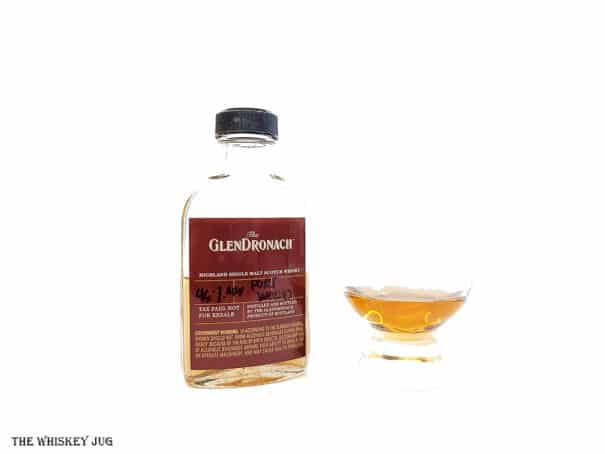White background tasting shot with the GlenDronach Port Wood bottle and a glass of whiskey next to it.