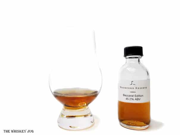 White background tasting shot with the Woodford Reserve Baccarat Edition bottle and a glass of whiskey next to it.