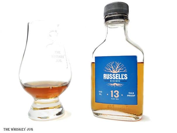 White background tasting shot with the Russell's Reserve 13 Years bottle and a glass of whiskey next to it.