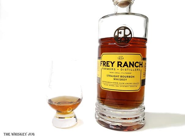 White background tasting shot with the Frey Ranch Bourbon bottle and a glass of whiskey next to it.