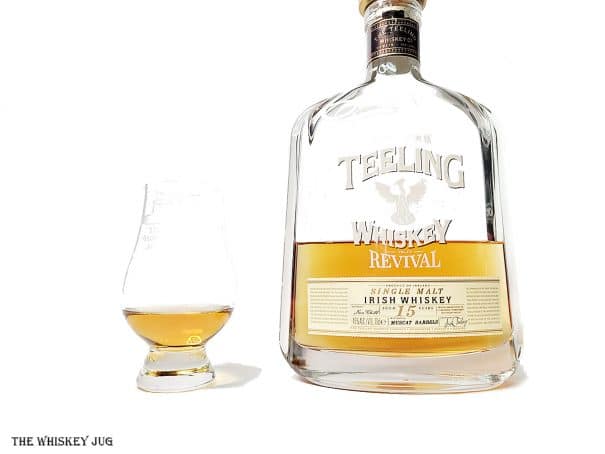 White background tasting shot with the Teeling Revival Volume IV Muscat Cask 15 Years bottle and a glass of whiskey next to it.