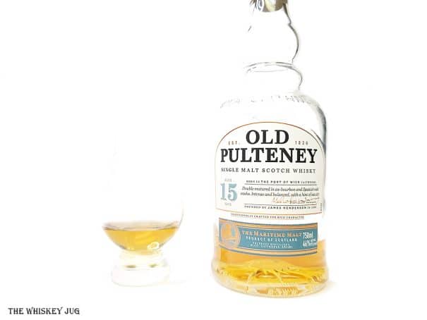 White background tasting shot with the Old Pulteney 15 bottle and a glass of whiskey next to it.