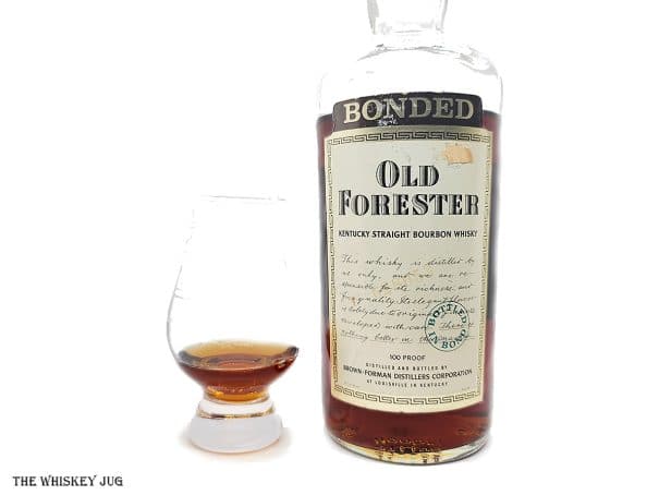 White background tasting shot with the 1975 Old Forester Bonded bottle and a glass of whiskey next to it.