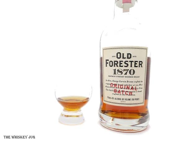 White background tasting shot with the Old Forester 1870 Original Batch bottle and a glass of whiskey next to it.