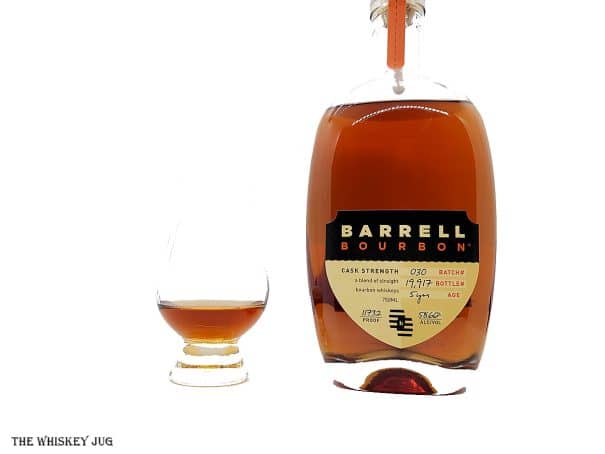 White background tasting shot with the Barrell Bourbon Batch 30 bottle and a glass of whiskey next to it.