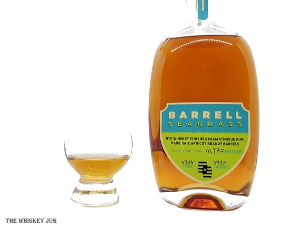 White background tasting shot with the Barrell Seagrass bottle and a glass of whiskey next to it.