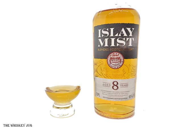 White background tasting shot with the Islay Mist 8 Years bottle and a glass of whiskey next to it.