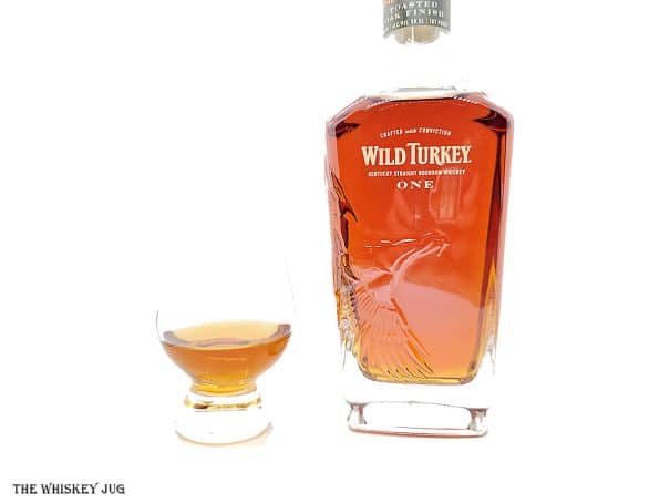 White background tasting shot with the Wild Turkey Master's Keep One bottle and a glass of whiskey next to it.