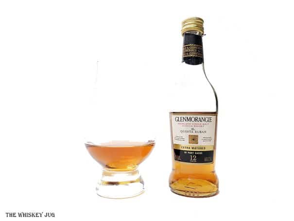 White background tasting shot with the Glenmorangie Quinta Ruban 12 Years bottle and a glass of whiskey next to it.