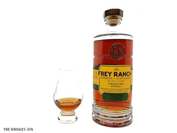 White background tasting shot with the Frey Ranch Rye Bottled-In-Bond bottle and a glass of whiskey next to it.