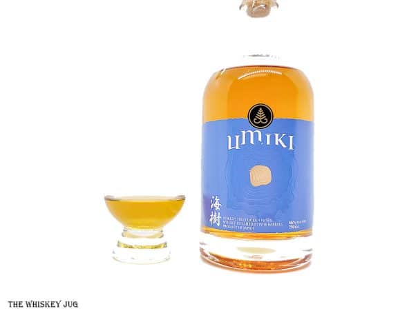 White background tasting shot with the Umiki "Ocean Fused" Whisky bottle and a glass of whiskey next to it.