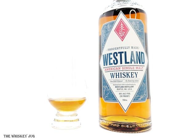 White background tasting shot with the Westland American Single Malt bottle and a glass of whiskey next to it.