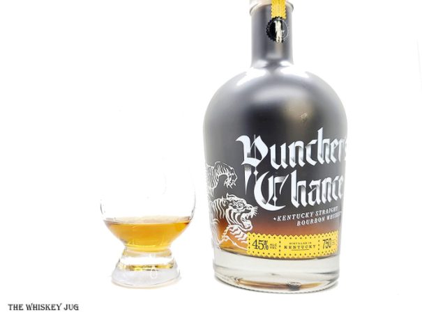 White background tasting shot with the Puncher's Chance Bourbon bottle and a glass of whiskey next to it.