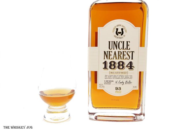 White background tasting shot with the Uncle Nearest 1884 Small Batch Whiskey bottle and a glass of whiskey next to it.
