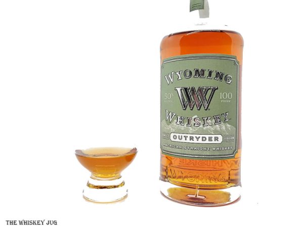 White background tasting shot with the Wyoming Whiskey Outryder 2021 bottle and a glass of whiskey next to it.