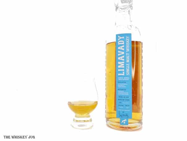 White background tasting shot with the Limavady Single Barrel Single Malt Irish Whiskey bottle and a glass of whiskey next to it.