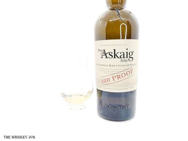 White background tasting shot with the Port Askaig 100 Proof bottle and a glass of whiskey next to it.