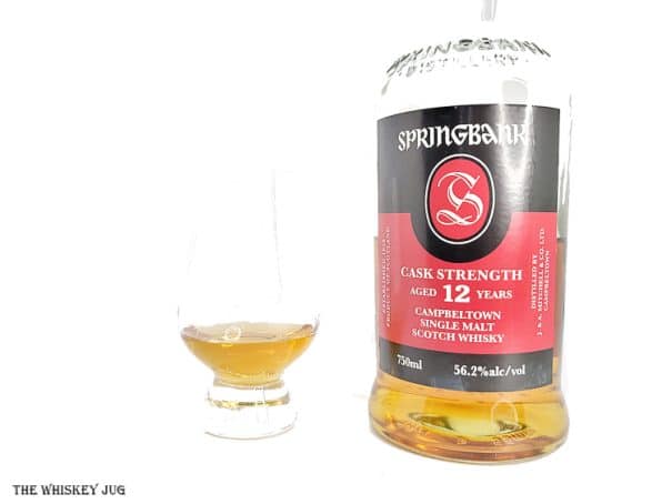 White background tasting shot with the Springbank 12 Years Cask Strength bottle and a glass of whiskey next to it.
