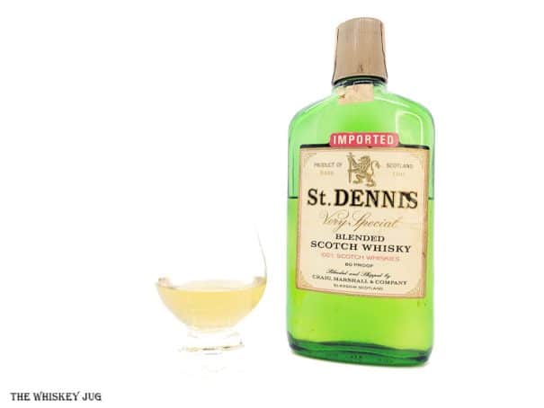 White background tasting shot with the St. Dennis Very Special Blended Scotch bottle and a glass of whiskey next to it.