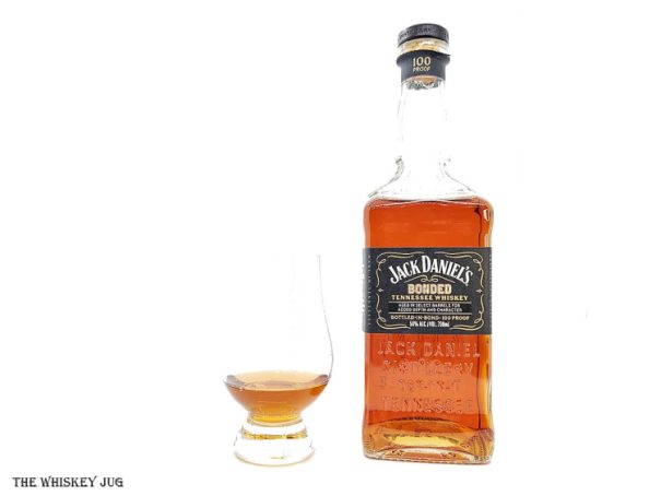 White background tasting shot with the Jack Daniel's Bonded Tennessee Whiskey bottle and a glass of whiskey next to it.